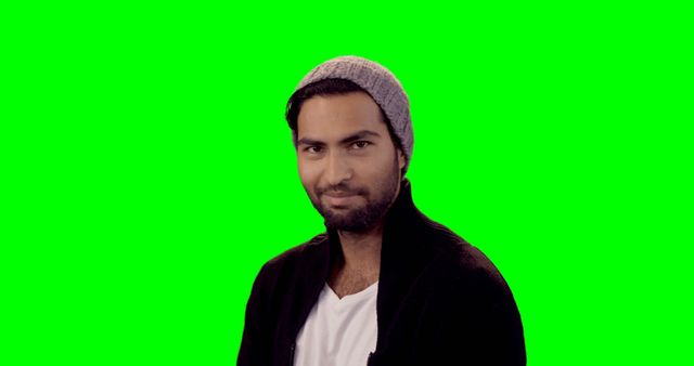 Man with a beanie hat and casual clothing standing against a green screen background. He is smiling and looking forward. Suitable for campaigns requiring a subject for green screen editing, lifestyle advertisements, tech demos, promotional materials or digital mock-ups.
