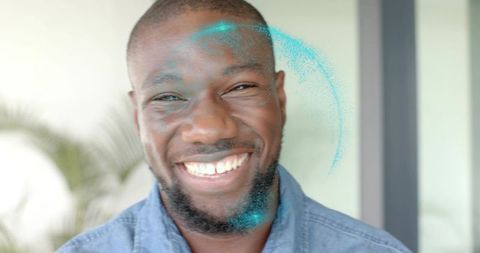 Smiling man wearing braces and denim shirt with teal pigment on face closeup headshot