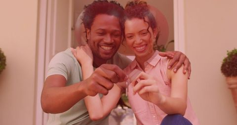 Happy couple celebrating new home with key and heart overlay