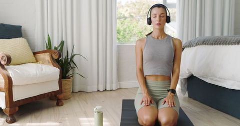 Woman Meditating with Headphones in Bright Minimalist Bedroom