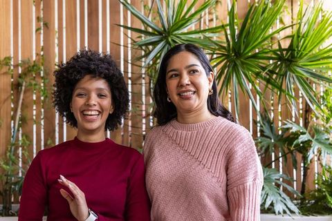 Diverse women laughing on green patio wearing cozy knit sweaters friendship lifestyle