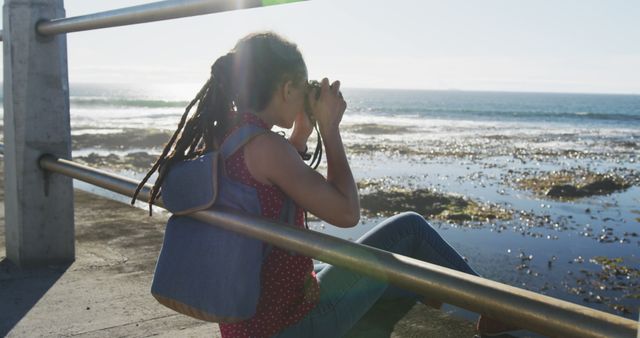 Young Woman Sitting by the Ocean Observing with Binoculars - Download Free Stock Images Pikwizard.com