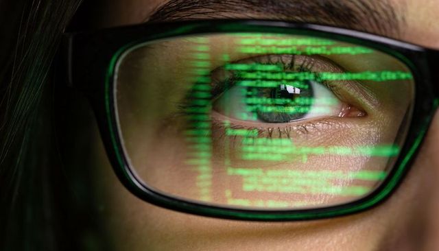 Closeup eye reflecting green code on glasses, cybersecurity programmer focusing on screen