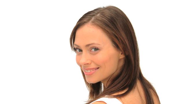 Young brunette woman smiling at the camera with a white background. Ideal for advertisements, beauty campaigns, lifestyle blogs, and social media profiles.