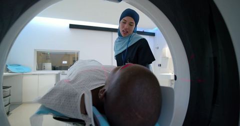 Muslim radiologic technologist aligning ct scanner lasers for african american patient