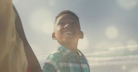 Joyful Son with Parent on Beach Looking Towards Camera