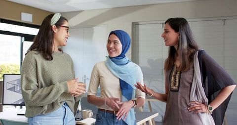 Diverse female colleagues collaborating in modern office with hijab and casual clothing