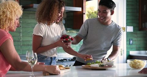 Diverse friends joyfully preparing food in kitchen gathering