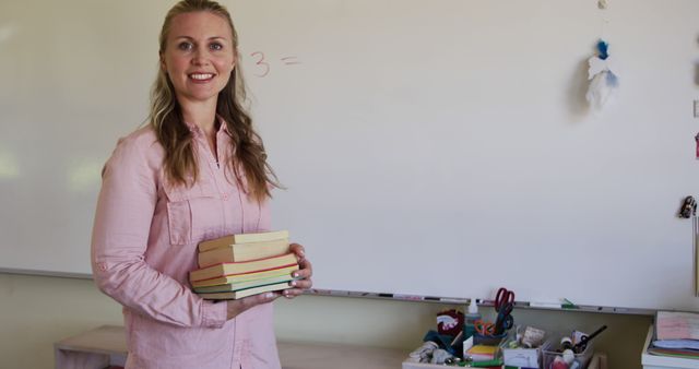 Smiling Female Teacher Holding Books in Classroom with Whiteboard - Download Free Stock Images Pikwizard.com