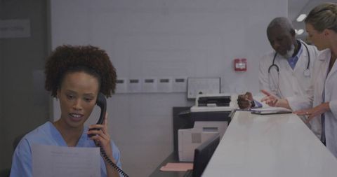 Medical receptionist coordinating with nurses and doctors at hospital
