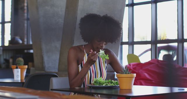 African american woman sitting in cafe eating a salad and smiling. digital nomad on the go