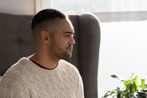 Mid-adult man sitting in sunlit wingback chair wearing cream cable knit sweater