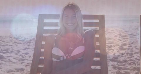 Woman relaxing on sunny beach lounge chair with ocean view