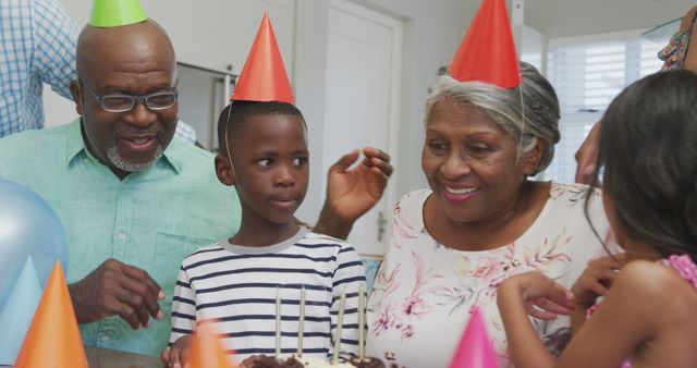 Multigenerational family celebrating a child's birthday. Grandparents and child smiling with party hats, enjoying time together. Ideal for stories about family traditions, celebration, and bonding moments.