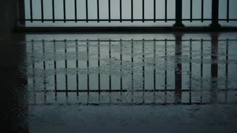 Balcony Railing Reflection Rippling on Wet Concrete Floor as Rain Creates Subtle Ripples