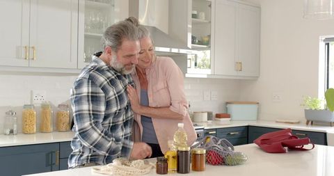 Senior Couple Bonding in Modern Kitchen with Preserves