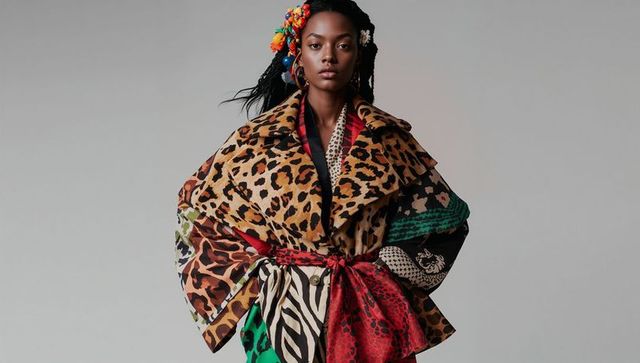 Black model posing wearing oversized patchwork animal-print coat with braids, hoops