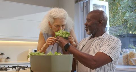 Smiling senior couple enjoying home herb gardening in kitchen