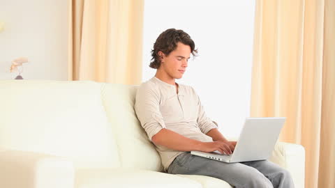 Young Man Using Laptop on Comfortable Sofa
