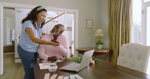 Senior couple discussing plans with laptop and documents