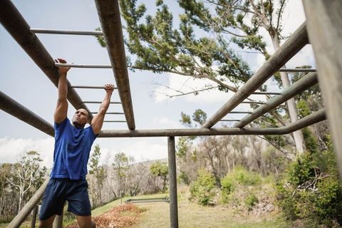 Man Traversing Monkey Bars on Outdoor Obstacle Course