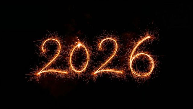 Writing 2026 with sparkler lightpainting, glowing orange sparks on black night backdrop