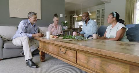 Diverse senior friends relaxing at home and enjoying coffee time