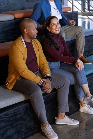 Diverse coworkers sitting on tiered seating chatting and smiling in casual meeting