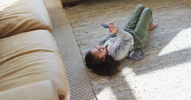 Happy girl laying on the floor,having fun and using smartphone. domestic life and leisure time concept.