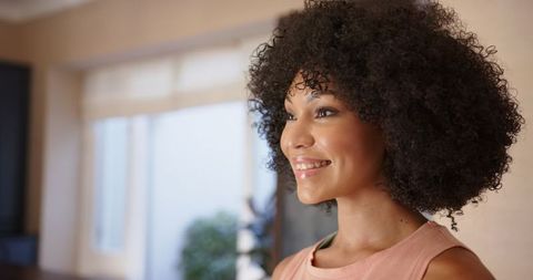 cheerful woman with curly hair smiling in bright interior - Download Free Stock Images Pikwizard.com
