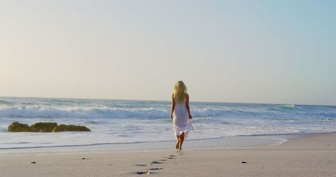 Serenity at Sunset: Woman Strolling along Tranquil Beachscape - Download Free Stock Images Pikwizard.com