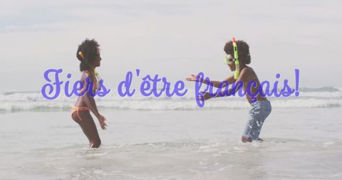 Joyful french children playing in ocean waves at beach