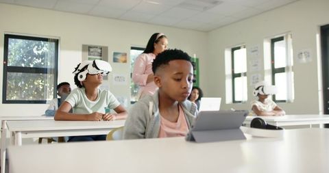 African American Students Using Tablets and VR Headsets in Modern Classroom Learning Space
