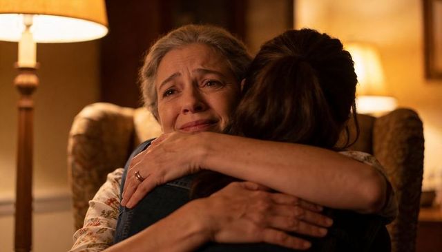 Older mother embracing adult daughter in warm lamp light conveying comfort and reassurance