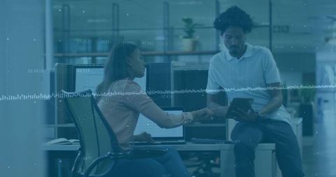 Coworkers collaborating over tablet and laptop with data waveform overlay in modern office
