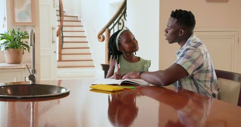 Father and Daughter Enjoying Homework Time Together at Kitchen Table