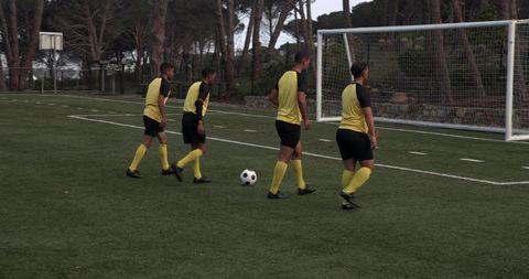 Four soccer players practicing teamwork on field