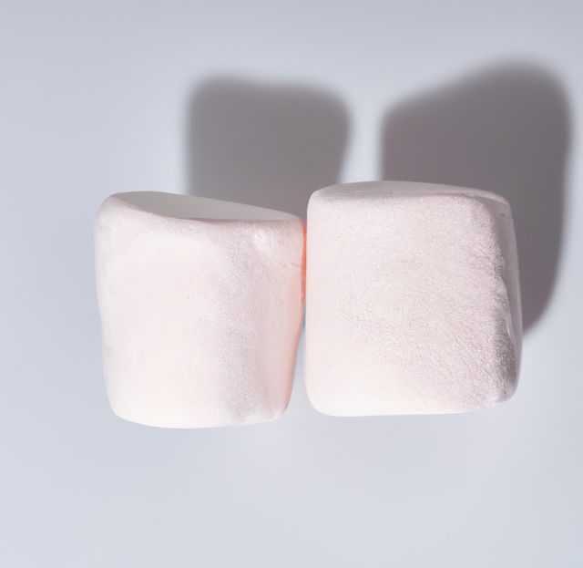 Close up of two pink marshmallows lying on white background. Sweets, food and drink concept.