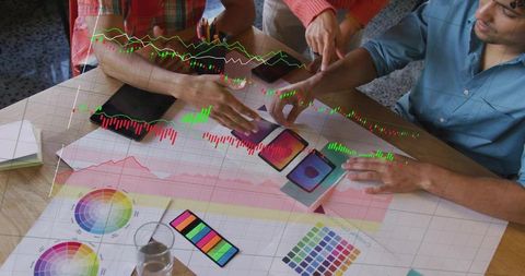 Design team collaborating over color swatches and mobile mockups with data overlays