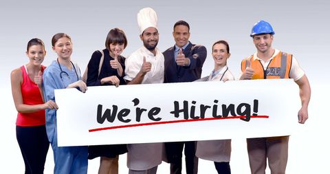 Diverse Professionals Holding We're Hiring Sign Showcasing Inclusivity