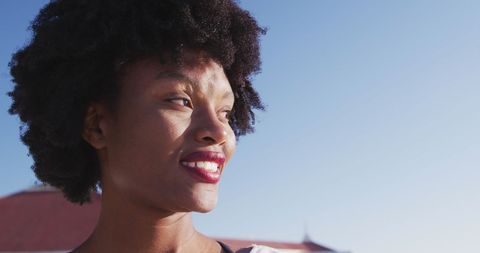 Smiling Young Woman Outdoors Enjoying Sunny Day with Blue Sky
