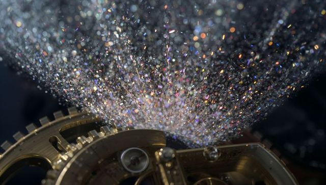 Macro brass watch gears gleaming through suspended glitter with jewel bearing detail