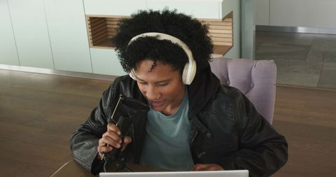 African american podcaster recording into mic with headphones in modern home studio