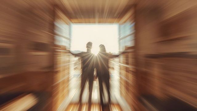 Couple standing in sunlit cabin doorway with radial blur and warm golden hour glow