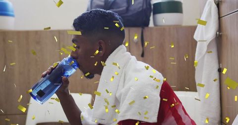 Confetti shower falls as football player recuperates with water in locker room