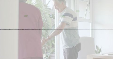 Smiling caregiver guiding elderly woman through sliding glass door to sunny garden patio