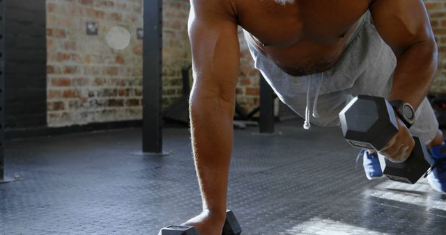 Athletic man performing push-up with dumbbells in gym - Download Free Stock Images Pikwizard.com