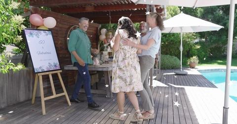 Backyard 60th Birthday Celebration with Friends Hugging by Pool and Festive Balloons