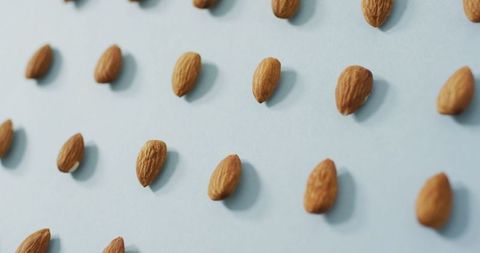 Almonds arranged on light blue background for healthy eating