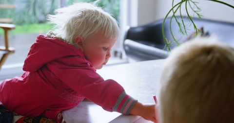 Blonde siblings drawing with crayons at home